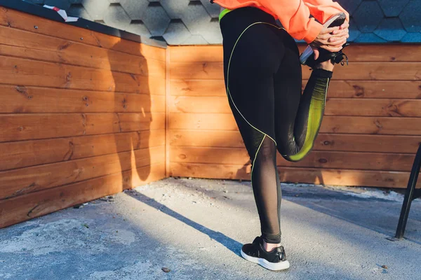 Νεαρή γυναίκα γυμναστικής δρομέας τεντώνει τα πόδια πριν τρέξει στην αποβάθρα, πίσω όψη, κενό χώρο. — Φωτογραφία Αρχείου