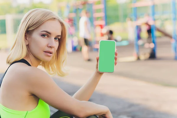 Müde Fitness-Frau nach dem Training und Smartphone mit grünem Bildschirm. — Stockfoto