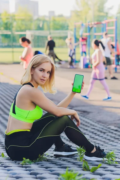 Müde Fitness-Frau nach dem Training und Smartphone mit grünem Bildschirm. — Stockfoto