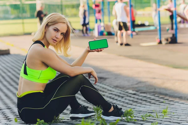 운동을 마치고 피곤 한 건강 한 여성이 녹색 화면이 달린 스마트폰을 사용하는 모습. — 스톡 사진