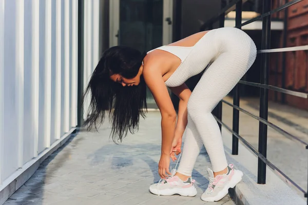 Egy fiatal nő szabadtéri sportokra készül a modern sétányon, közel a lakásához.. — Stock Fotó