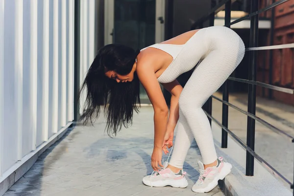 A young woman is preparing for outdoor sports on the modern promenade near her apartment complex. — Stock Photo, Image