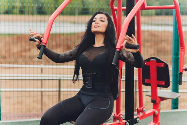 Mujer sonriendo mientras hace ejercicio en la parte superior del cuerpo usando la máquina de pesas afuera. —  Fotos de Stock
