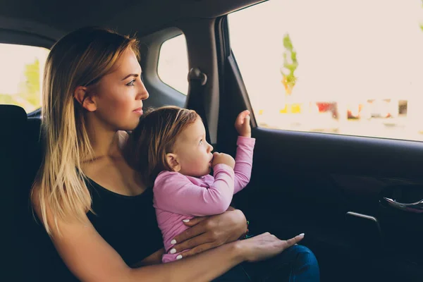 Petit bébé tout-petit fille regarde par la fenêtre de la voiture avec sa mère. — Photo