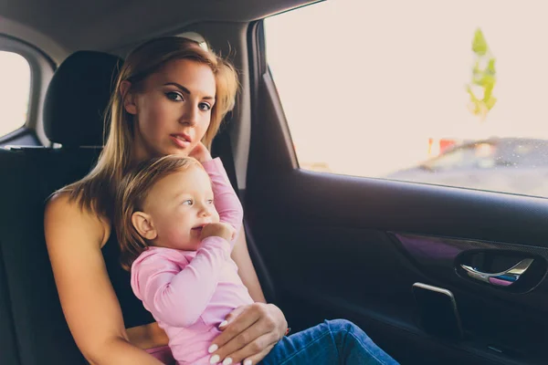 Petit bébé tout-petit fille regarde par la fenêtre de la voiture avec sa mère. — Photo