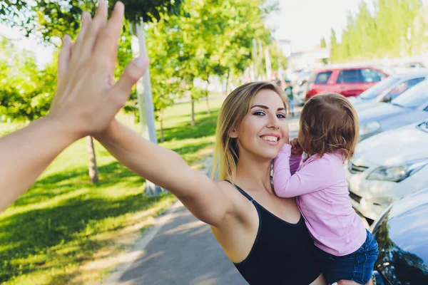 Mooie vrouw houdt een jaar oude baby in haar armen in het park. Moederschap en familie. Zorg en ontwikkeling van het kind. — Stockfoto