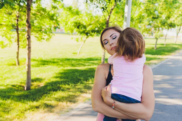 Mooie vrouw houdt een jaar oude baby in haar armen in het park. Moederschap en familie. Zorg en ontwikkeling van het kind. — Stockfoto