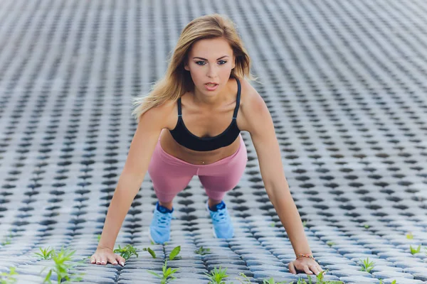 Çekici ve güçlü bir kadın yaz parkında spor öncesi esneme hareketleri yapıyor. Spor konsepti. Sağlıklı yaşam tarzı. — Stok fotoğraf