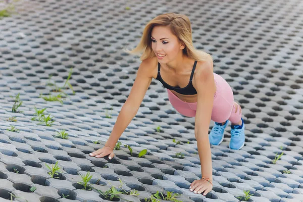 Attraktiv och stark kvinna som sträcker sig innan kondition i sommarparken. Sportkoncept. En hälsosam livsstil. — Stockfoto