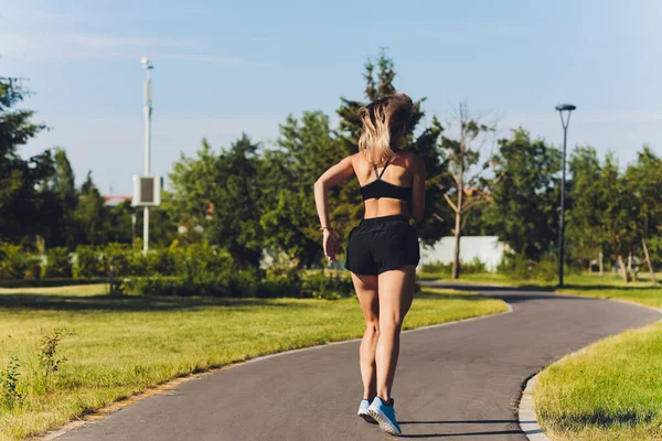 Junge Frau joggt im Sommer im Park. — Stockfoto