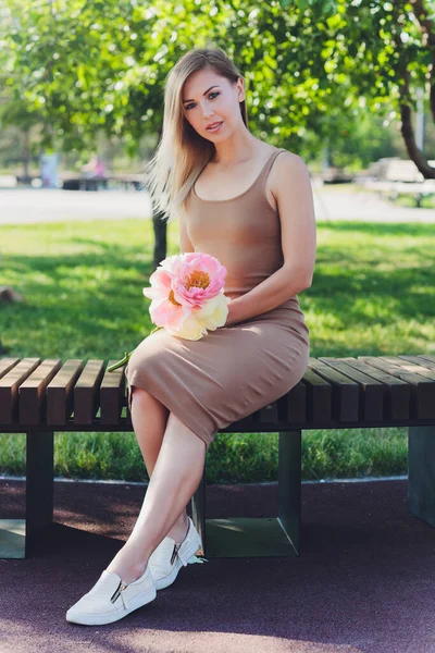 Aantrekkelijke vrouw zit o boeket van pioenroos bloemen. — Stockfoto