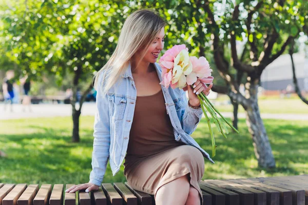 魅力的な女性は牡丹の花の花束を座って. — ストック写真