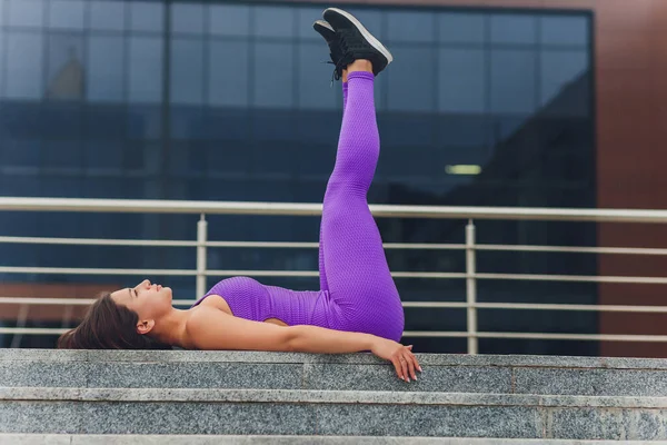 Krásná mladá fitness žena dělá břišní cvičení při ležení na stadionu. — Stock fotografie