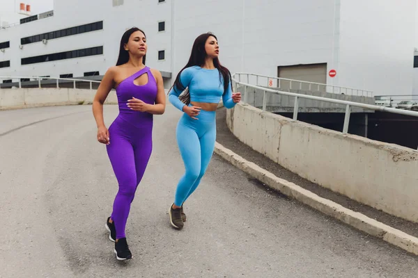 두 명의 여자 운동 선수가 도시의 잔디 위에 있는 도시 계단 위에서 달리기 훈련을 받고 있다. — 스톡 사진