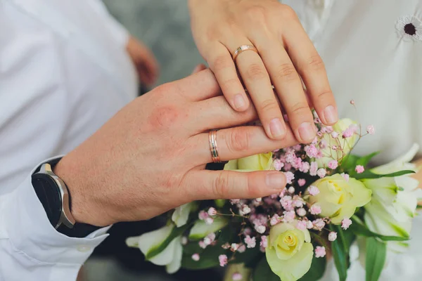 Close-up middendeel van een pasgetrouwd stel met trouwringen en boeket. — Stockfoto