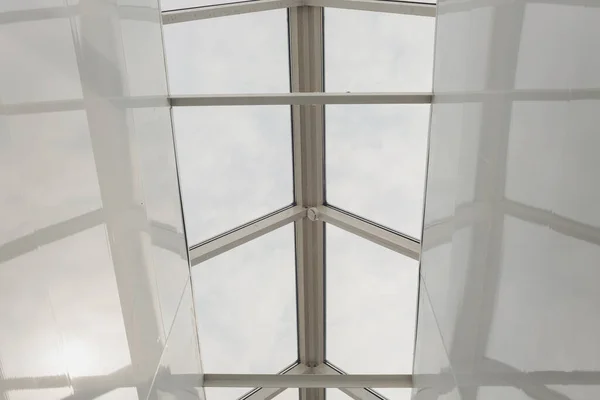Blick hinauf zum blauen wolkenverhangenen Himmel durch modernes quadratisches Deckenfenster. — Stockfoto