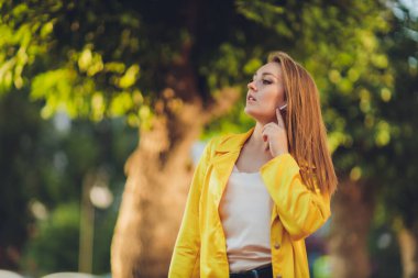 Moda eğilimleri gösteriyor. Koyu saçlı, çekici bir kadın, parlak sarı tüylü pelerinli..