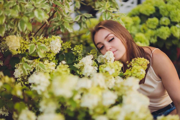 Uma menina com cabelo azul cheira as flores florescentes no jardim na primavera . — Fotografia de Stock