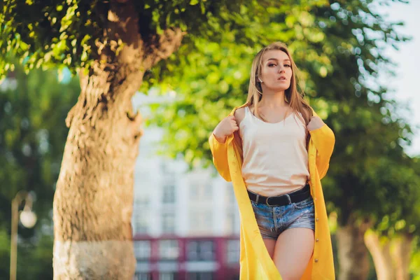 Mostrando tendencias de moda. Mujer atractiva de pelo oscuro posando en una capa mullida de color amarillo brillante. — Foto de Stock