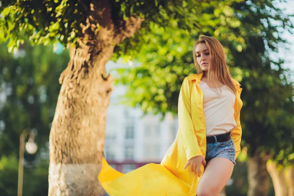 ファッションの傾向を示す。ダークヘア魅力的な女性姿勢で明るい黄色ふわふわクローク. — ストック写真