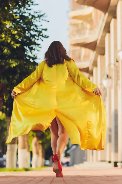 패션의 경향을 보여 줍니다. 밝은 노란색 솜털 코트를 입고 누워 있는 검은 머리의 매력적 인 여성. — 스톡 사진