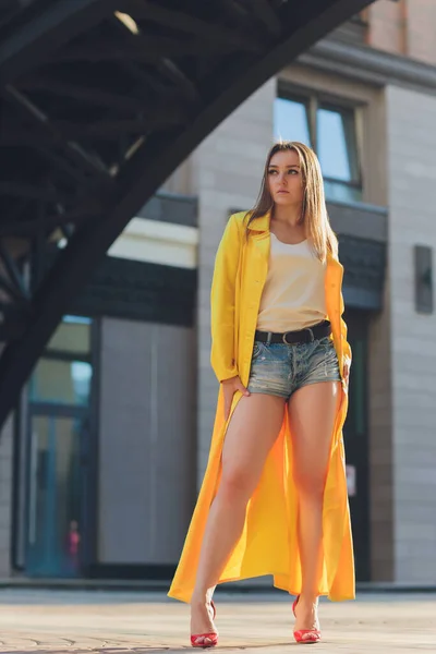 Visualizzazione delle tendenze della moda. Bruna donna attraente postura in giallo brillante soffice mantello. — Foto Stock