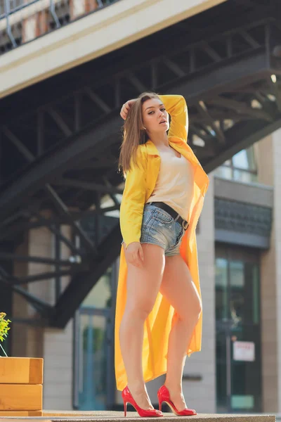 Visualizzazione delle tendenze della moda. Bruna donna attraente postura in giallo brillante soffice mantello. — Foto Stock