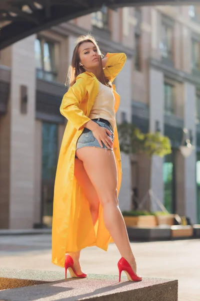 Εμφάνιση τάσεις της μόδας. Σκούρα μαλλιά ελκυστική γυναίκα στέκεται σε φωτεινό κίτρινο χνουδωτό μανδύα. — Φωτογραφία Αρχείου