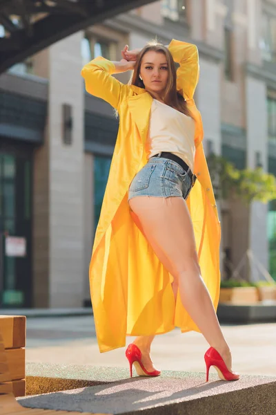 Displaying fashion tendencies. Dark-haired attractive woman posturing in bright yellow fluffy cloak. — Stock Photo, Image