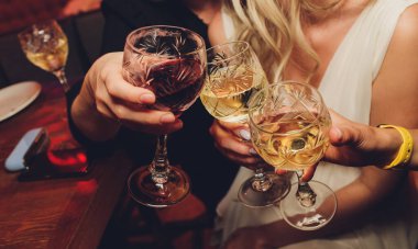 Bokeh arkaplanının önünde kadeh tokuşturup şampanya içen bir grup insanı yakından çek. Yaşlı insanların elleri.