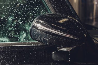 Modern lüks arabanın yan aynasındaki boya korumalı film kurulumunu kapatın. PPF, boyalı arabalara uygulanan poliüretan filmdir. Boyayı taş parçalarından, böcek lekelerinden ve aşınmadan korumak için.