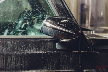 Modern lüks arabanın yan aynasındaki boya korumalı film kurulumunu kapatın. PPF, boyalı arabalara uygulanan poliüretan filmdir. Boyayı taş parçalarından, böcek lekelerinden ve aşınmadan korumak için.