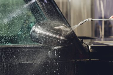 Modern lüks arabanın yan aynasındaki boya korumalı film kurulumunu kapatın. PPF, boyalı arabalara uygulanan poliüretan filmdir. Boyayı taş parçalarından, böcek lekelerinden ve aşınmadan korumak için.