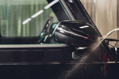 Modern lüks arabanın yan aynasındaki boya korumalı film kurulumunu kapatın. PPF, boyalı arabalara uygulanan poliüretan filmdir. Boyayı taş parçalarından, böcek lekelerinden ve aşınmadan korumak için.