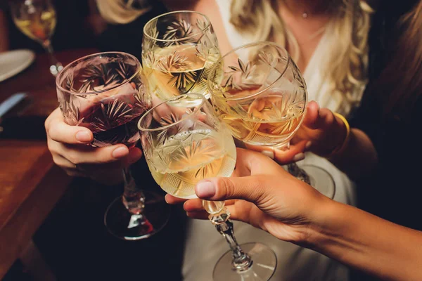 Nahaufnahme einer Gruppe von Menschen, die vor Bokeh-Hintergrund Gläser mit Wein oder Champagner klappern. Ältere Hände. — Stockfoto