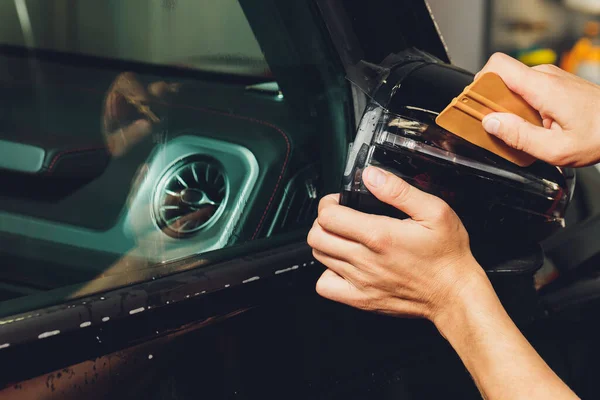 Close up of paint protection film installation on side mirror of modern luxury car. PPF is polyurethane film applied to painted of car to protect the paint from stone chips, bug splatter, and abrasion