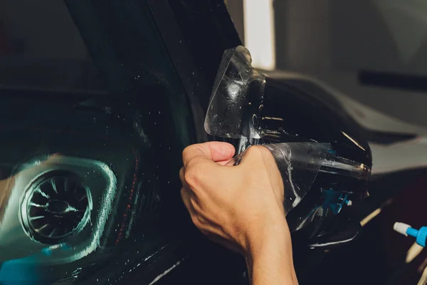 Detailní záběr instalace fólie na boční zrcátko moderního luxusního auta. PPF je polyuretanový film nanášený na lakovaný automobil, který chrání barvu před kamínky, štěrbinami a oděrem — Stock fotografie