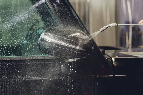 Modern lüks arabanın yan aynasındaki boya korumalı film kurulumunu kapatın. PPF, boyalı arabalara uygulanan poliüretan filmdir. Boyayı taş parçalarından, böcek lekelerinden ve aşınmadan korumak için.