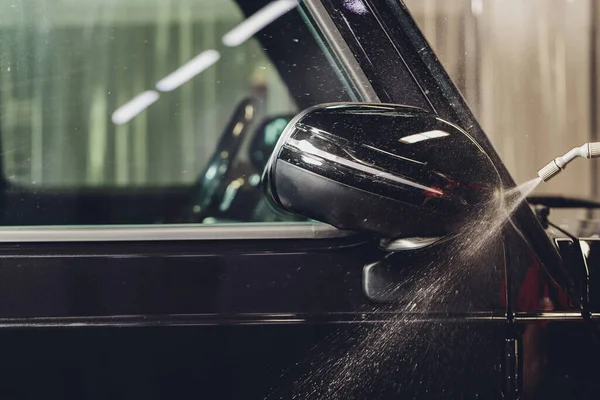 Modern lüks arabanın yan aynasındaki boya korumalı film kurulumunu kapatın. PPF, boyalı arabalara uygulanan poliüretan filmdir. Boyayı taş parçalarından, böcek lekelerinden ve aşınmadan korumak için.