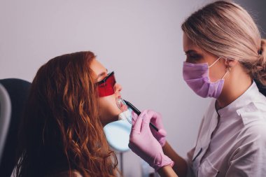 Diş beyazlatma için dişçiye giden bir kadının yakın plan portresi, diş beyazlatma prosedürü..