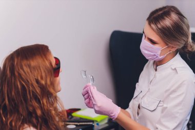 Kadın dişçi hastalarının dişlerinde çalışıyor..