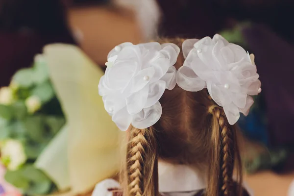 Cheveux tressés en deux tresses avec des arcs blancs coiffure écolière vacances. — Photo