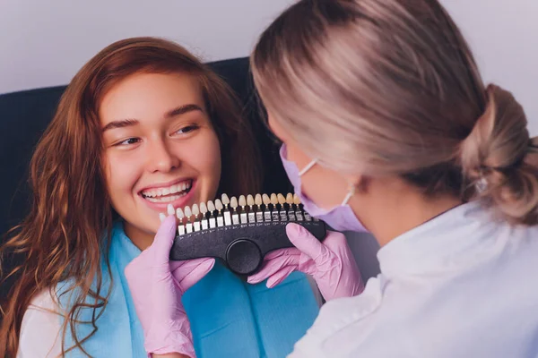 Il dentista confronta l'ombra dei denti dei pazienti con i campioni per il trattamento dello sbiancamento. — Foto Stock