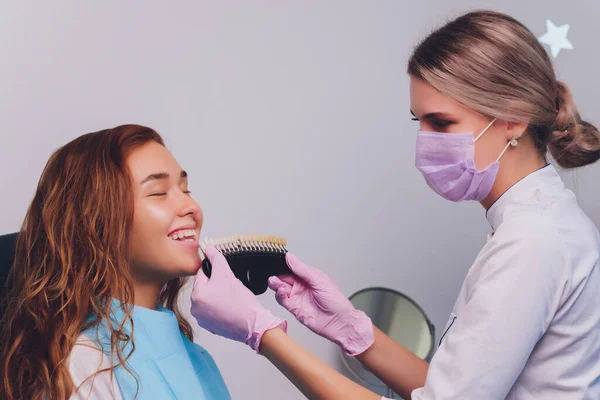 Der Zahnarzt vergleicht die Zahnschattierung der Patienten mit Proben für die Bleichbehandlung. — Stockfoto