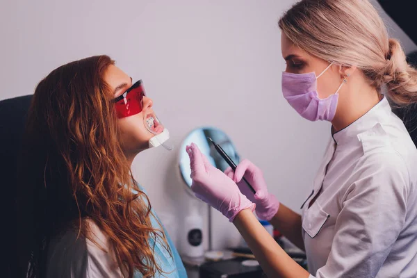 Primo piano ritratto di una paziente in visita dal dentista per lo sbiancamento dei denti in clinica, procedura di sbiancamento dei denti. — Foto Stock