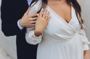 Damat düğün töreninde gelinlerin elini tutuyor. El ele tutuşun ve birlikte yürüyün. Kendine güven. Gelinin elinde siyah elmaslı beyaz bir altın yüzük var..
