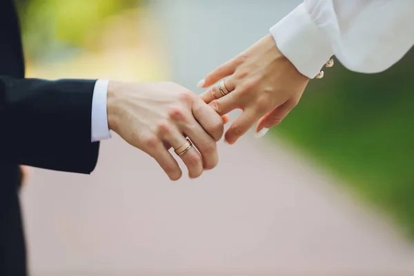 Brudgummen håller brudens hand vid bröllopsceremonin. Håll händerna och gå tillsammans. Förtroende. På brudens hand är en vit guldring med svarta diamanter. — Stockfoto