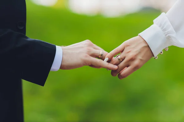 El novio sostiene la mano de las novias en la ceremonia de la boda. Coged las manos y caminad juntos. Confianza. En la mano de la novia es un anillo de oro blanco con diamantes negros. —  Fotos de Stock