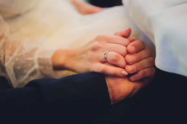 O noivo segura a mão das noivas na cerimônia de casamento. Dêem as mãos e andem juntos. Confiança. Na mão da noiva é um anel de ouro branco com diamantes pretos. — Fotografia de Stock