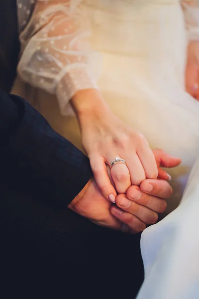 Pan młody trzyma pannę młodą za rękę podczas ceremonii ślubnej. Trzymajcie się za ręce i idźcie razem. Pewność siebie. Na ręce panny młodej jest biały złoty pierścień z czarnymi diamentami. — Zdjęcie stockowe
